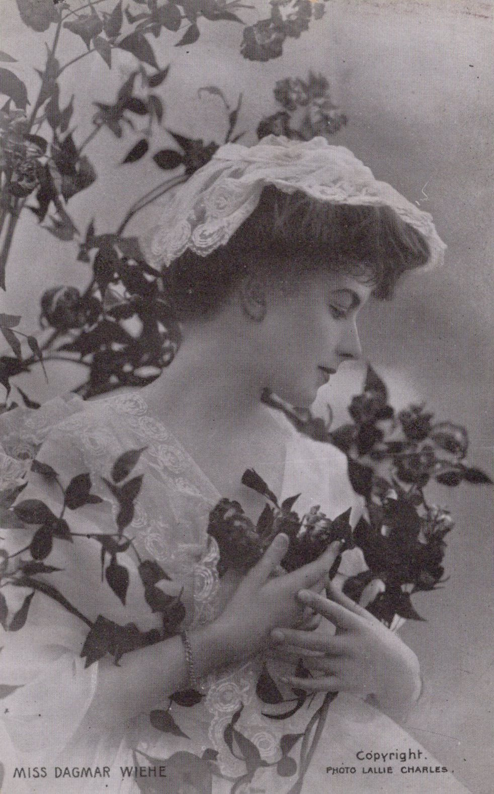 Vintage photograph of a woman holding flowers with a decorative hat.