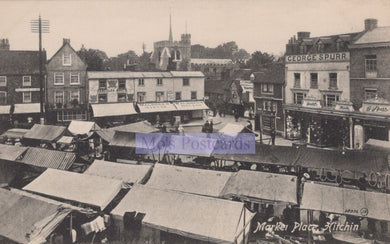 Vintage black and white photo of a market scene with tents and buildings in the background.