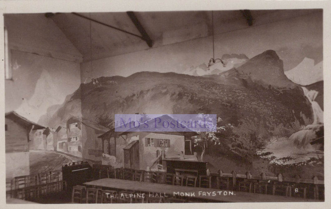 Vintage photograph of an indoor setting with a mountain mural on the wall, labeled 'The Alpine Hall, Monk Fryston'.