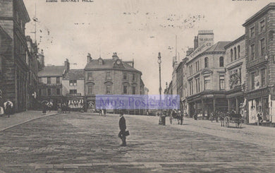 Vintage black and white photograph of a town square with people and buildings.