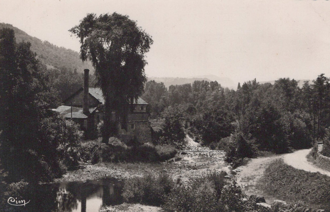 Vintage black and white photograph of a rural landscape with a building, trees, and a path.