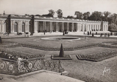 Historical black and white photograph of a grand building with gardens and people around