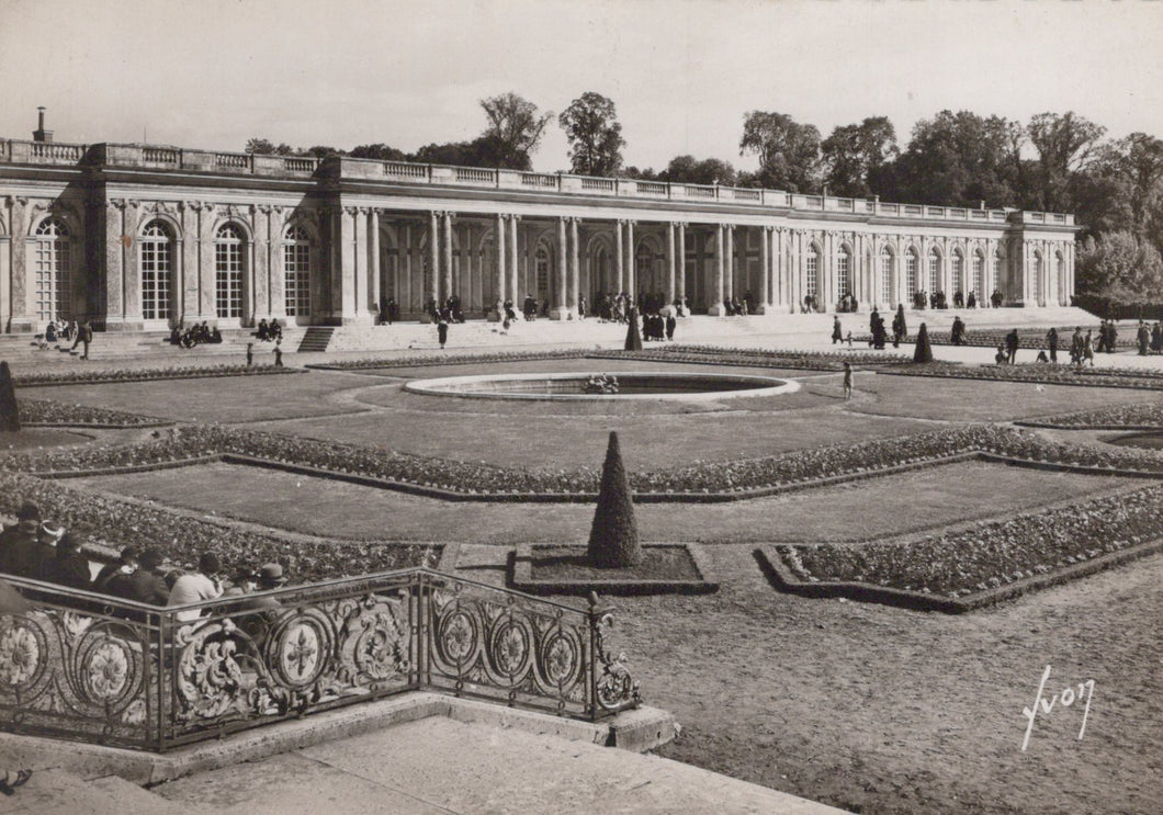 Historical black and white photograph of a grand building with gardens and people around