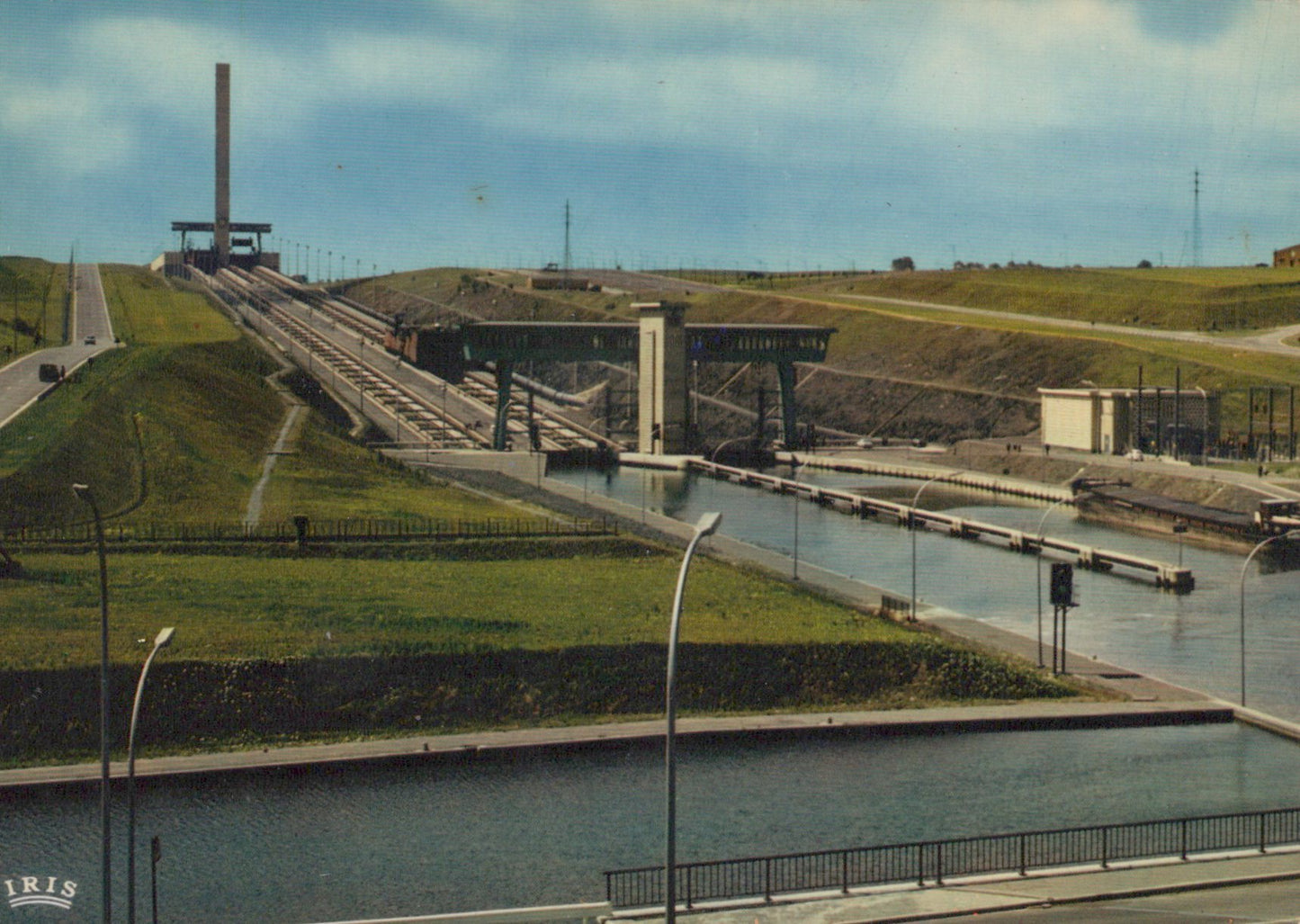 Historical photograph of a canal lock system with grassy area and road in the foreground.