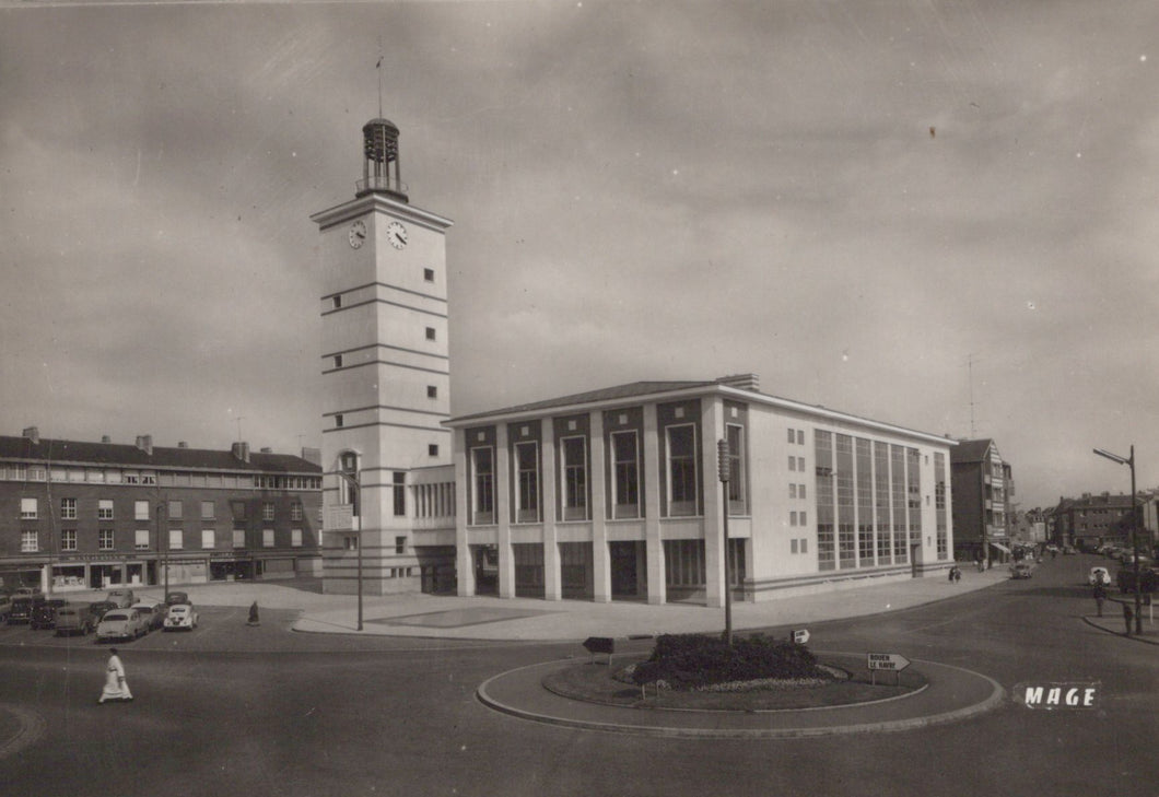 Vintage black and white photo of a large building with a clock tower and surrounding street scene.