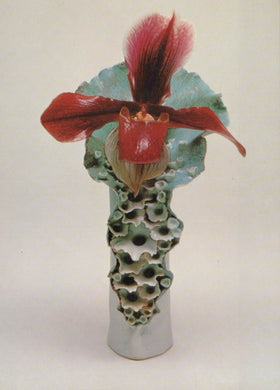 Ceramic vase with a textured base and red floral design on a white background