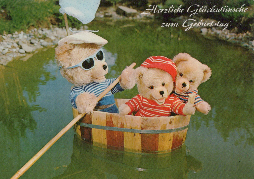 Three teddy bears in a wooden barrel on water with German text above