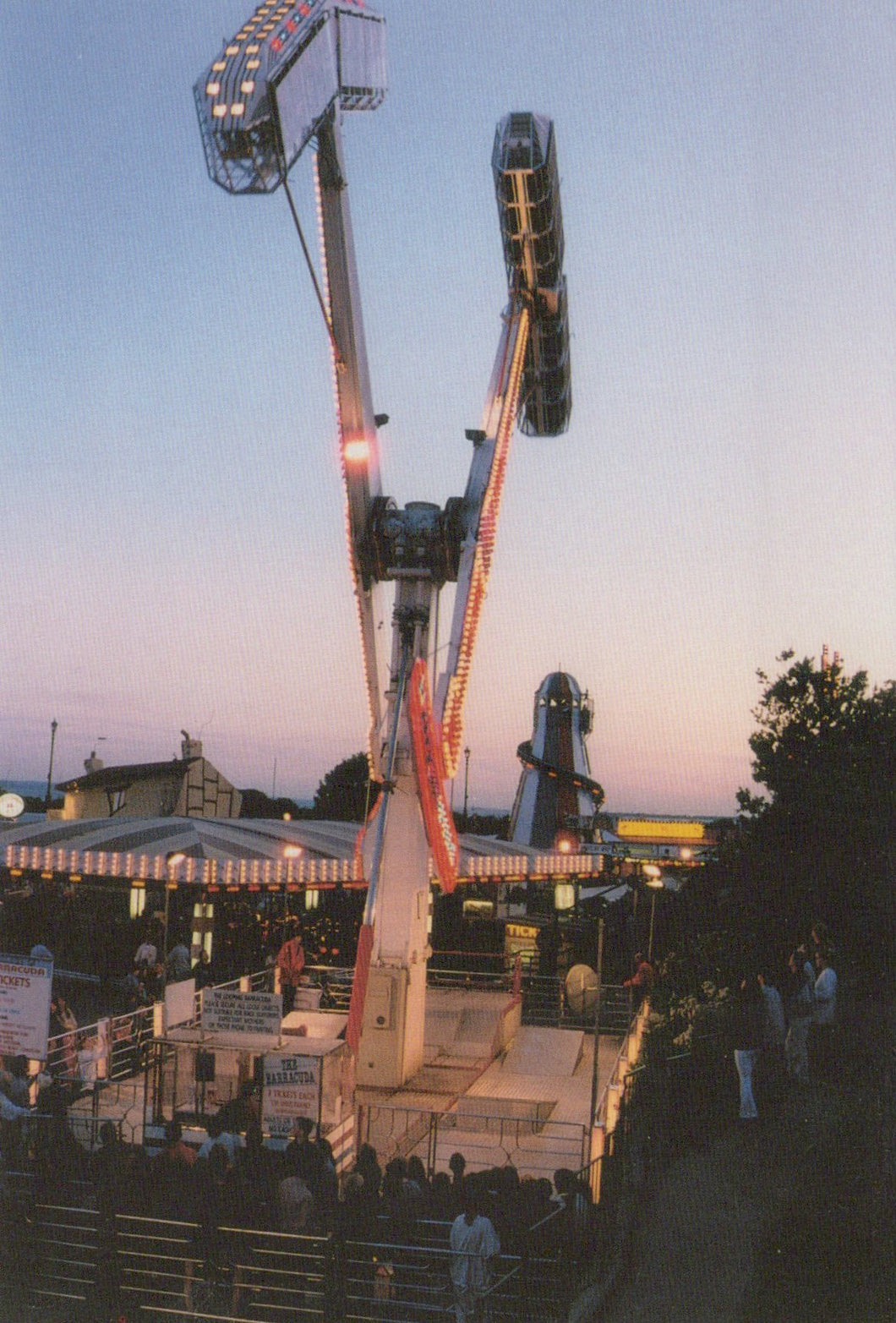 Ferris wheel at an amusement park during dusk with people around