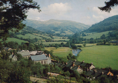 Village nestled in a valley with rolling hills and a river