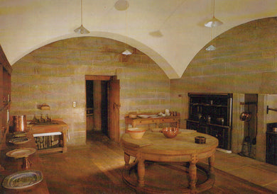 Historic kitchen with stone walls, wooden table, and vintage appliances.