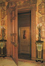 Load image into Gallery viewer, Decorative interior with open wooden door, ornate walls, and candle holders.
