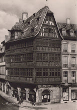 Load image into Gallery viewer, Historical black-and-white photograph of a corner building with wooden facade on a street.
