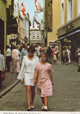 Two women walking down a busy street with shops and people in the background.