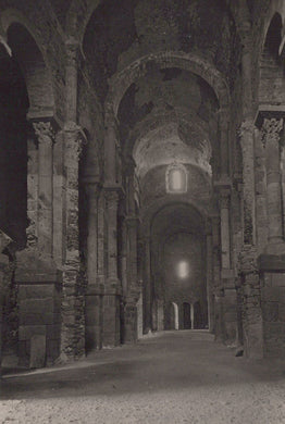 Dark interior of a stone building with arches and columns