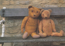 Load image into Gallery viewer, Two teddy bears sitting on a wooden bench against a stone wall.

