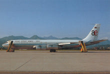 Load image into Gallery viewer, Passenger airplane on a runway with mountains in the background

