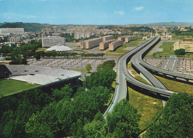 Aerial view of a cityscape with a highway and greenery