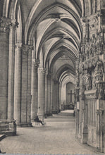 Load image into Gallery viewer, Narrow stone hallway with high vaulted ceilings and decorative columns, leading to a cross.
