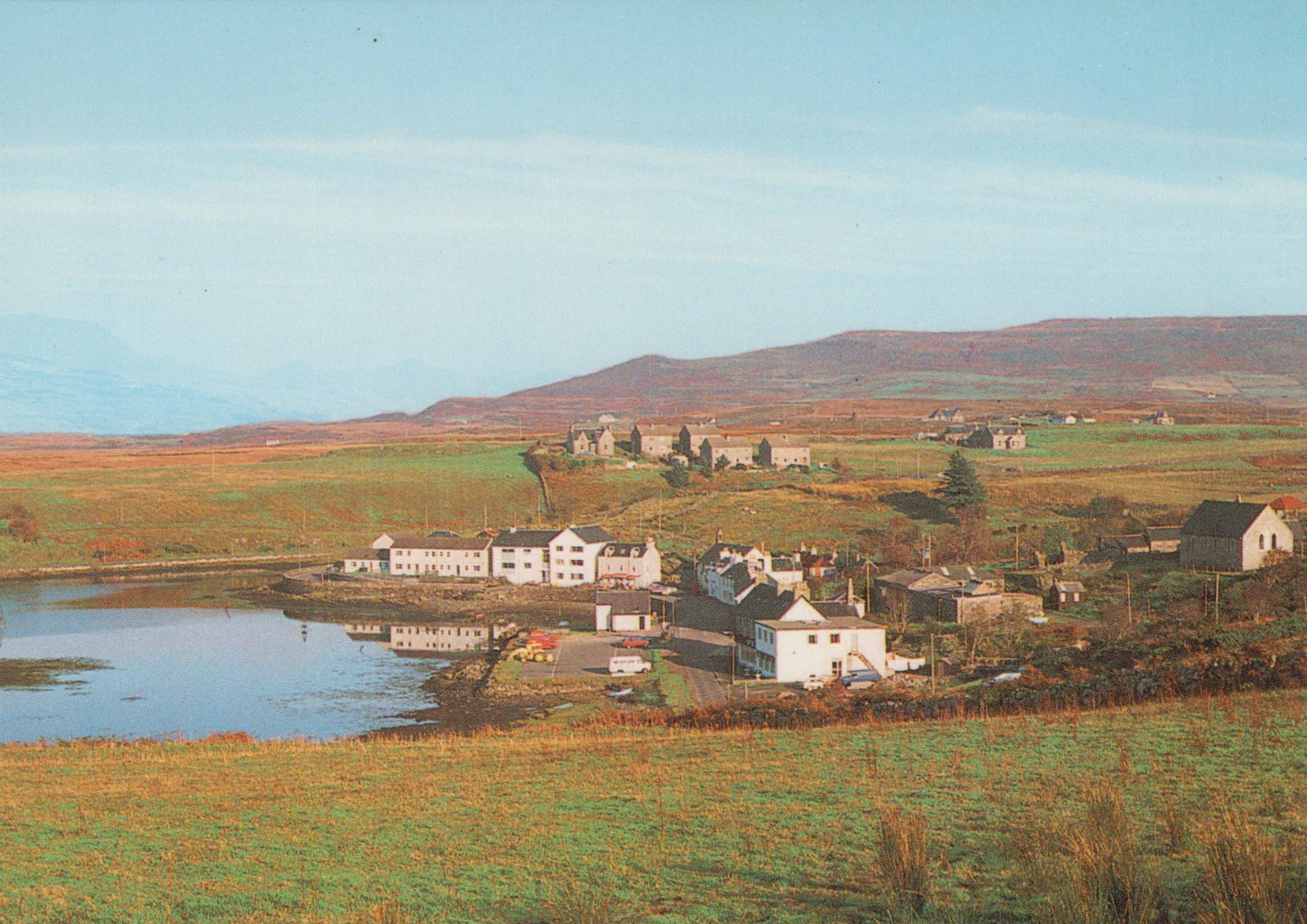 Scenic view of a village by a lake with mountains in the background