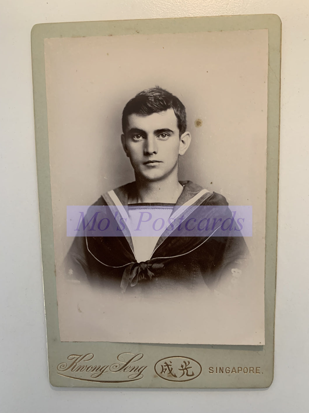 Vintage portrait of a young man in a sailor suit with 'Henry Levy' branding on a white background.