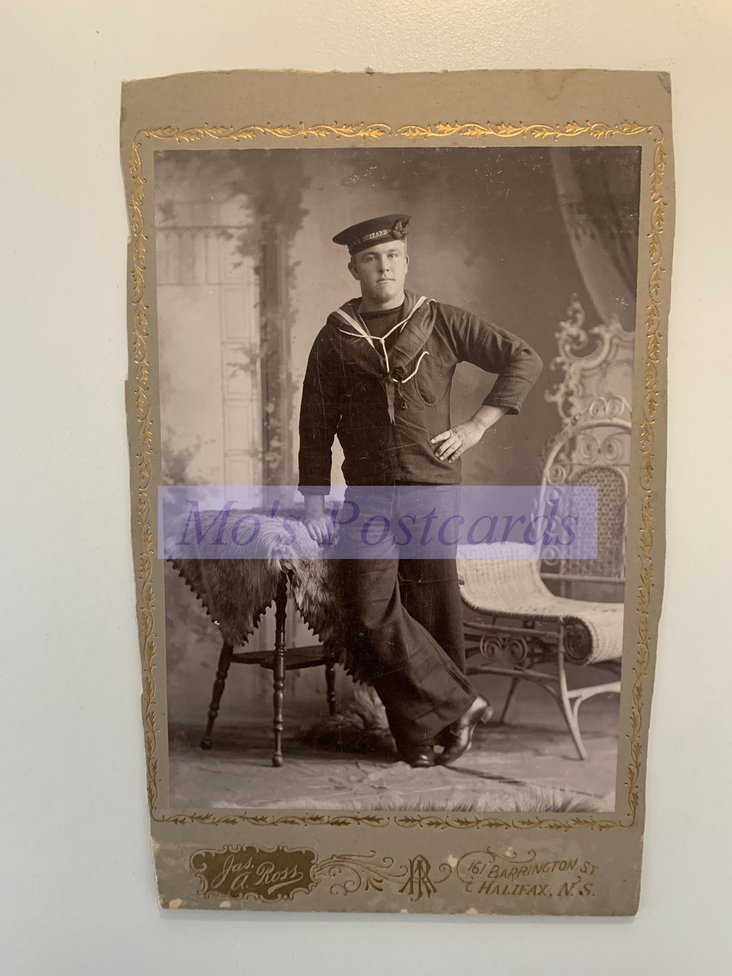 Vintage photo of a person in a sailor suit with decorative frame and watermark.