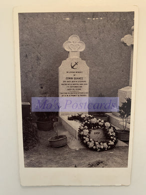 Grave with headstone and wreath in a cemetery, featuring 'Mo's Postcards' watermark.