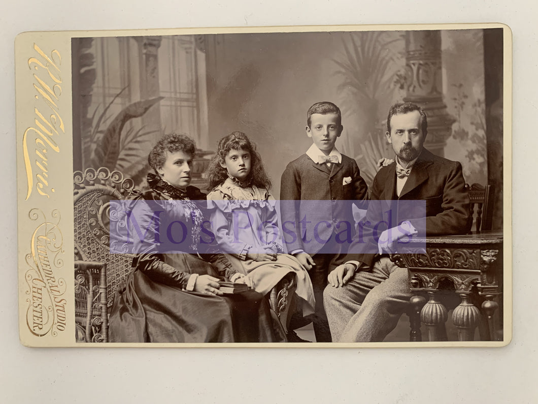 Vintage family portrait with four individuals in formal attire, sitting together.