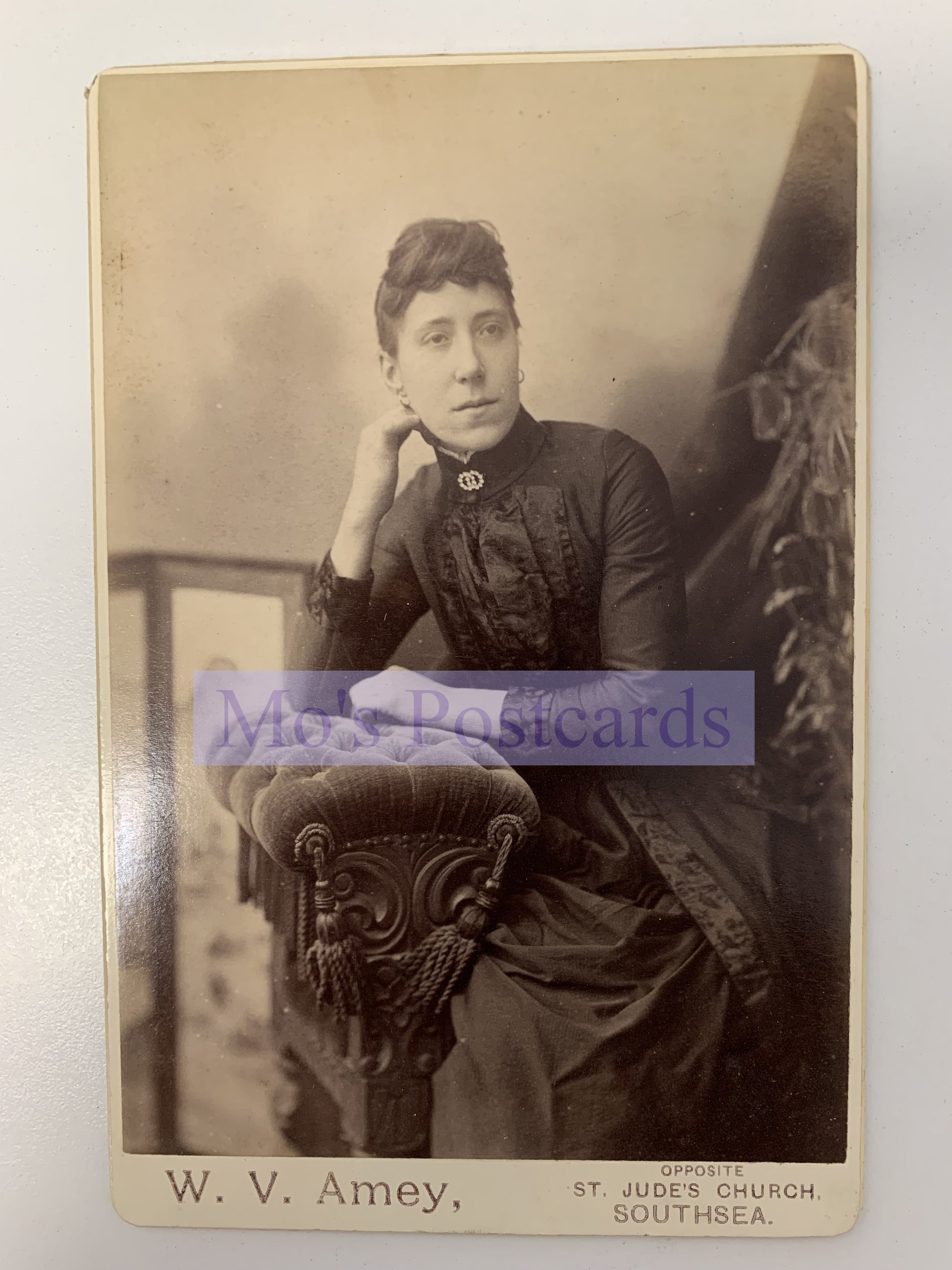 Vintage photograph of a woman sitting on a decorative chair with 'W. V. Amey' branding.