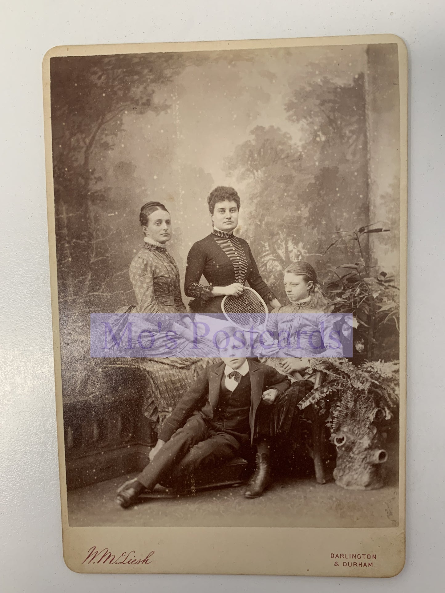 Vintage black and white photograph of three people sitting together with decorative elements.